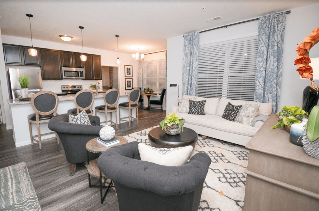 a living room and kitchen with a couch and chairs
