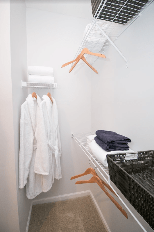 a small closet with robes and towels and a rack with wooden hangers