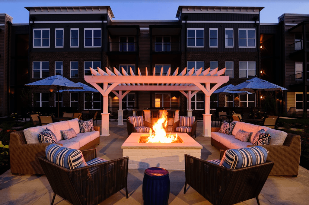 a fire pit in the middle of a patio with chairs and umbrellas