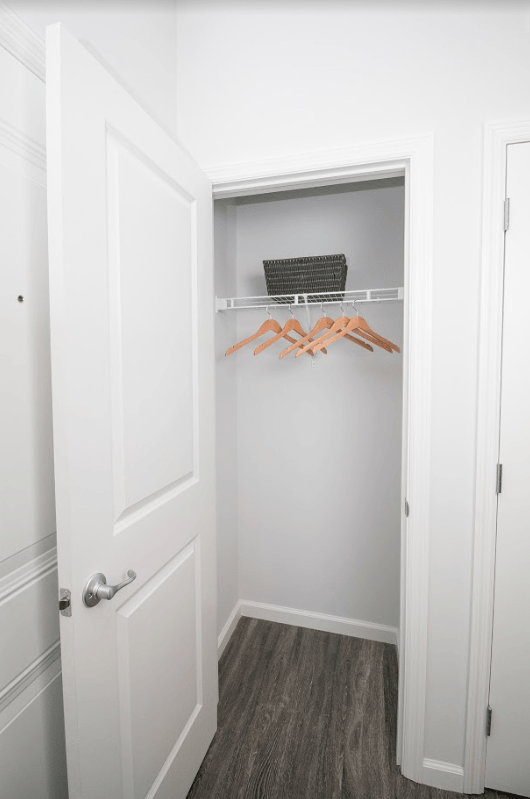 a closet in a small room with white walls and wood floors