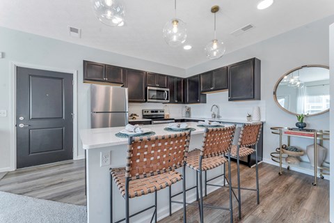 a kitchen with a long island with bar stools and a stainless steel refrigerator