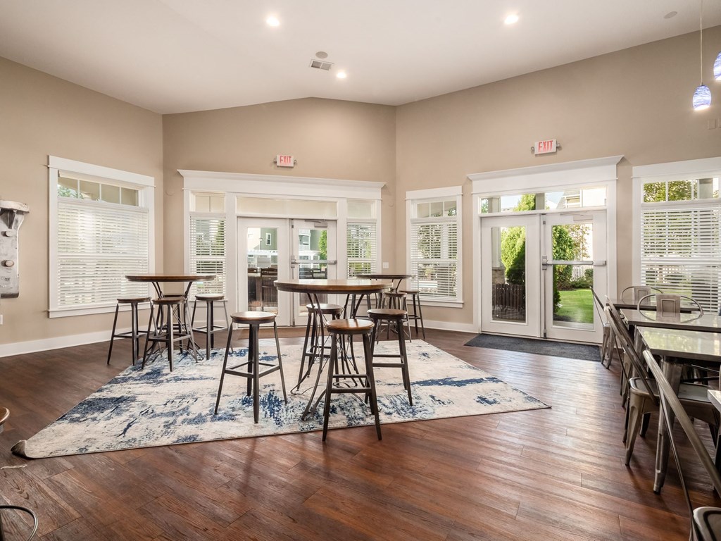 an empty living room with tables and chairs and windows