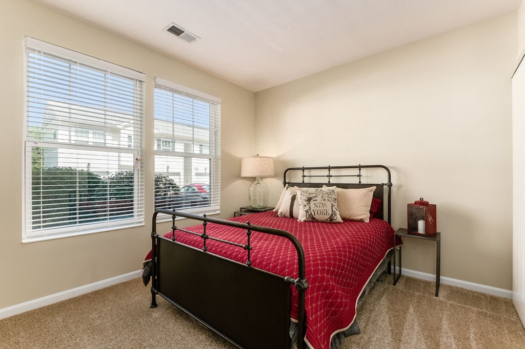 a bedroom with a bed and two windows