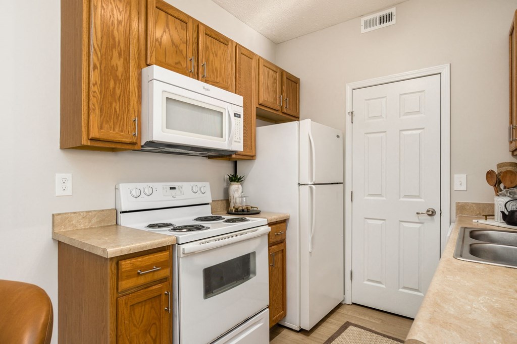 a kitchen with white appliances and wooden cabinets and a white refrigerator