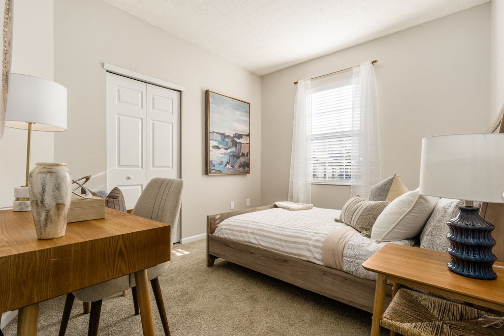 a bedroom with a bed and a desk and a window