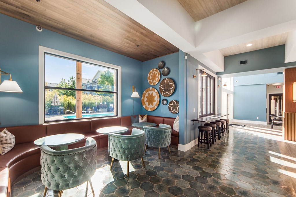 a lounge area with blue walls and tables and chairs and a large window