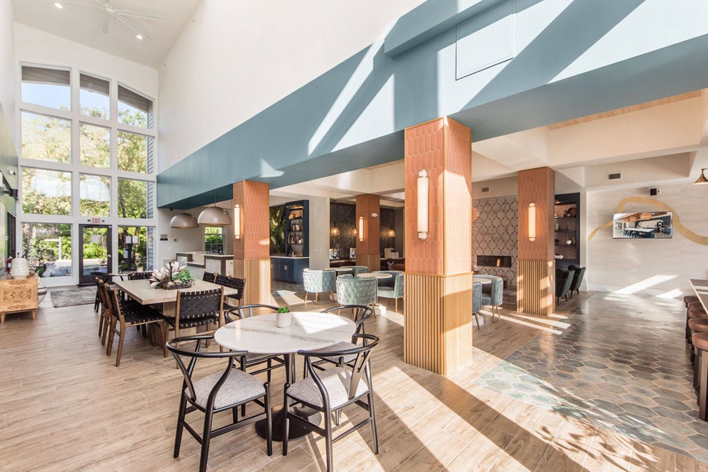 the lobby of a hotel with tables and chairs and large windows