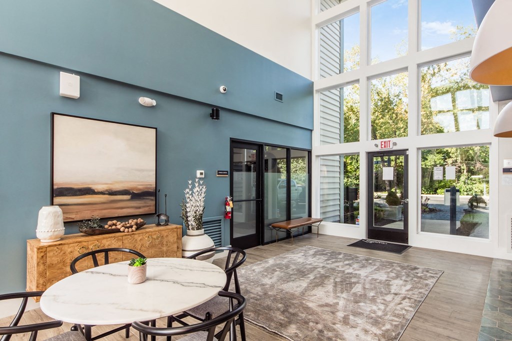 a living room with large windows and a table and chairs