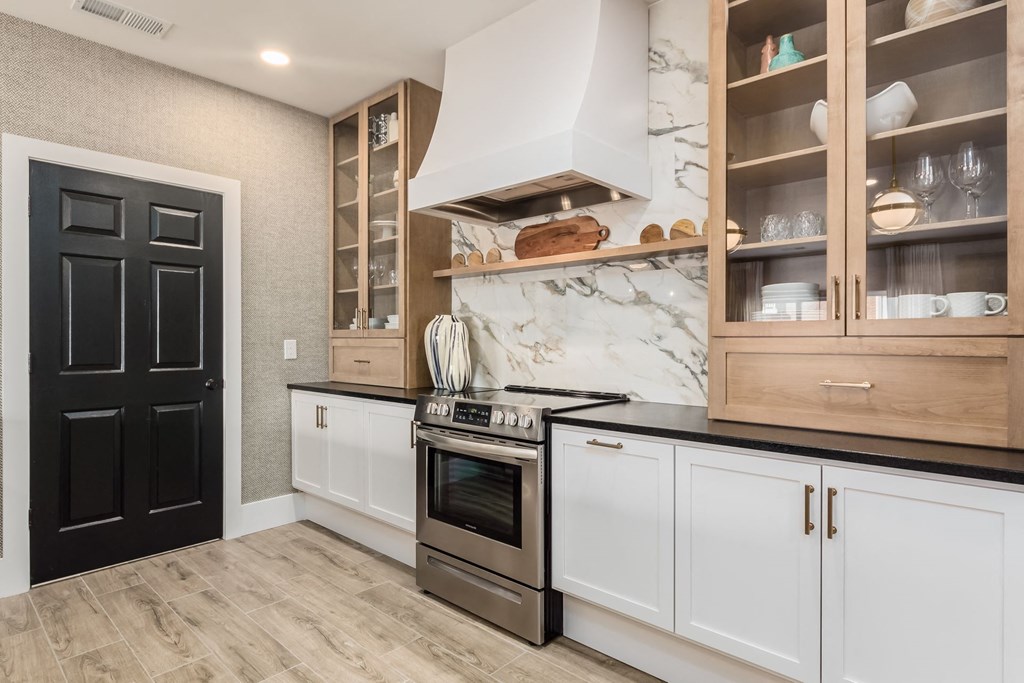 a kitchen with white cabinets and stainless steel appliances and a black door