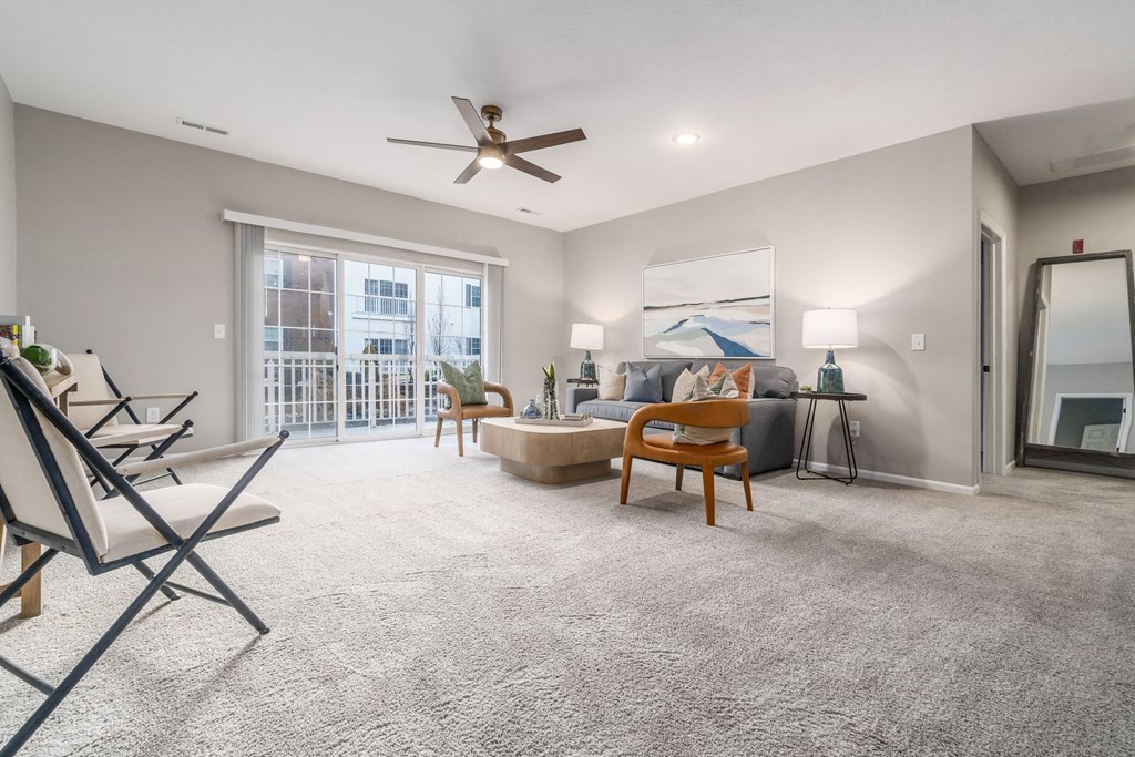 a living room with a couch and chairs and a ceiling fan