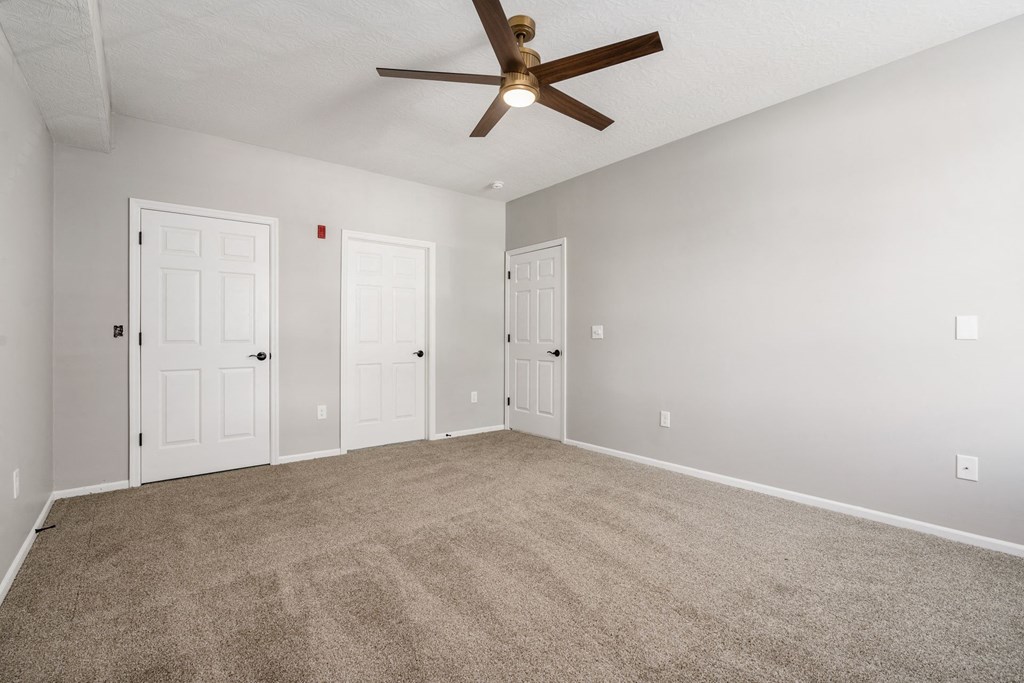 Residences of Gahanna main bedroom looking toward attached bath and walk-in closet with new flooring, paint and modern new ceiling fan