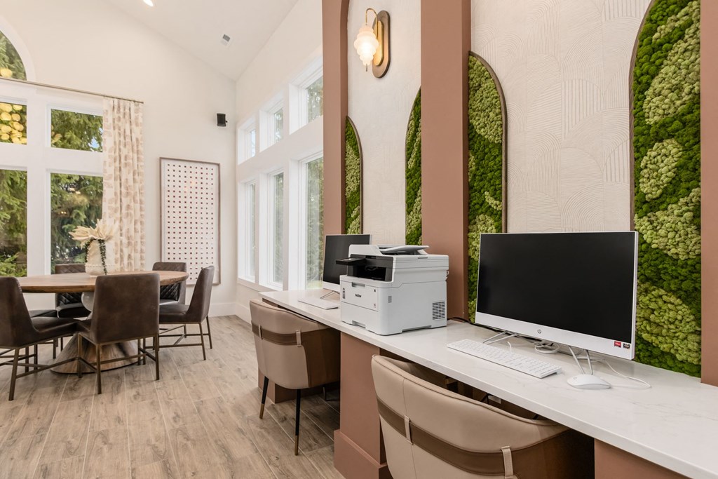 a computer and printer on a desk in a room with a table and chairs