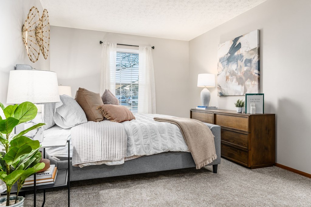 a bedroom with a bed and a dresser and a window