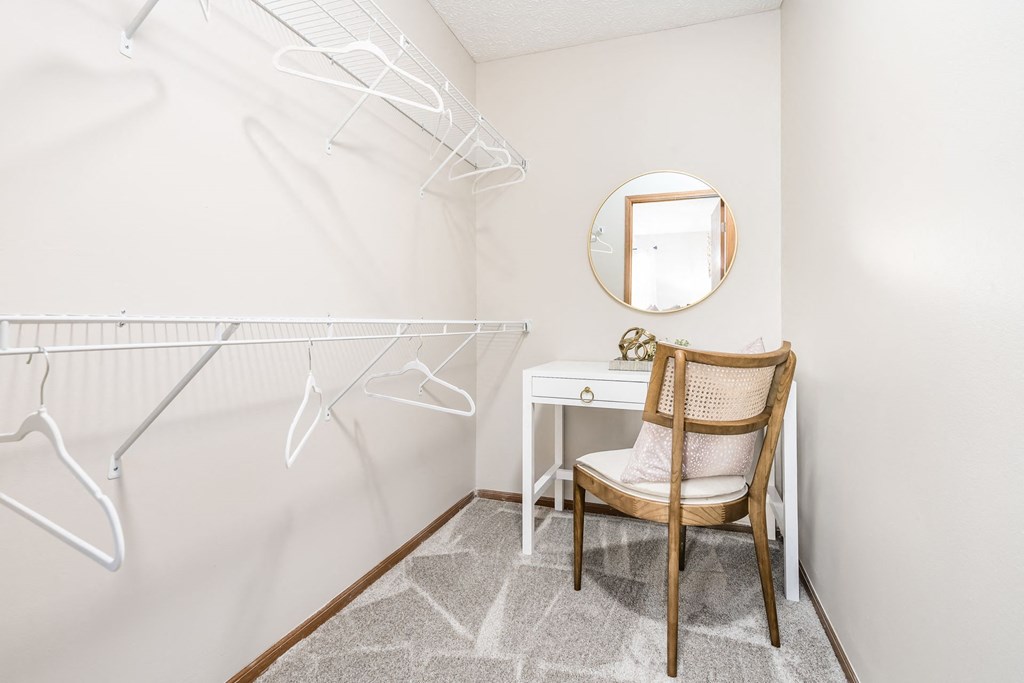 a white closet with a chair and a white desk and a mirror