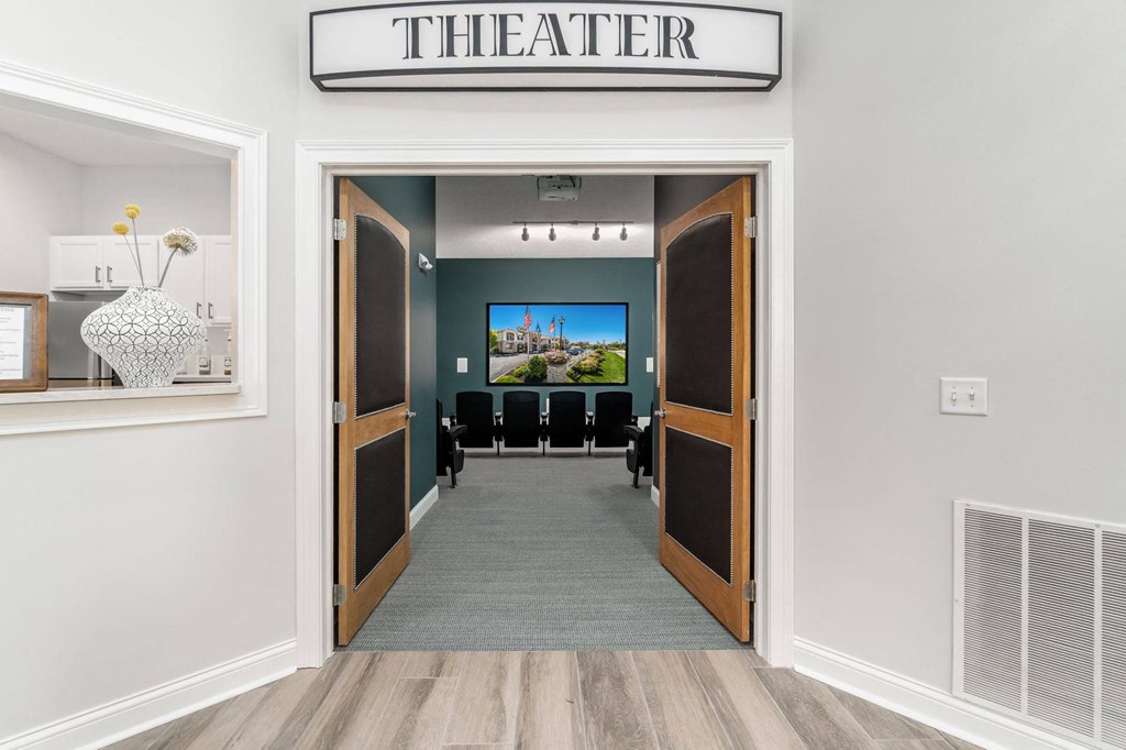 the entrance to the theater with chairs and a tv on the wall