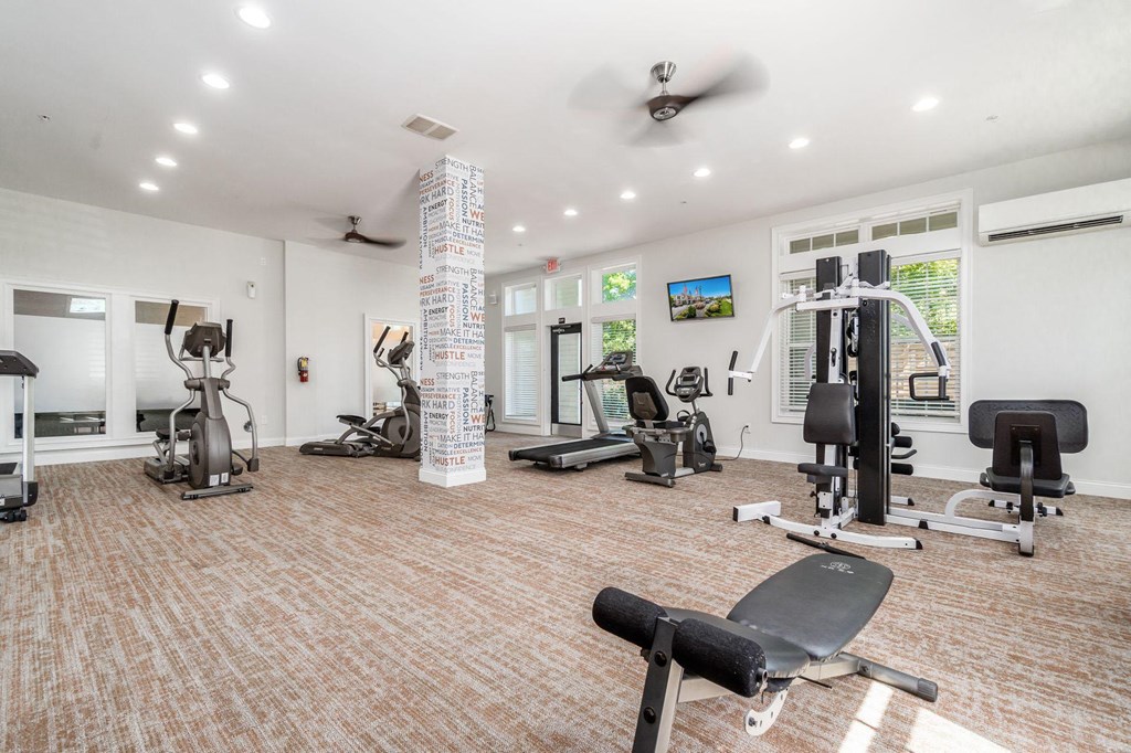 a gym with weights and cardio equipment in a room with windows