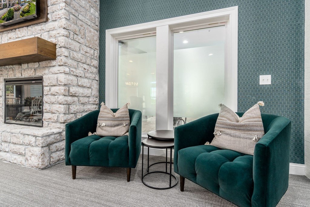 a living room with two green chairs and a fireplace