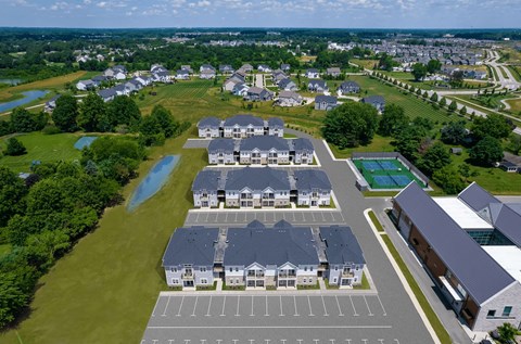 A bird's eye view of a residential area with houses, a swimming pool, and a parking lot.