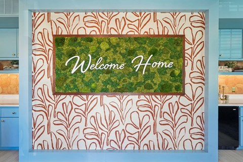 A wall with a leaf pattern and a sign that says Welcome Home.