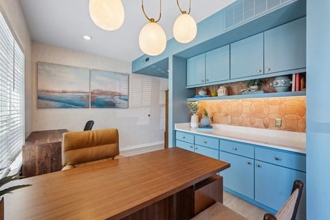 A room with a wooden table and blue cabinets.