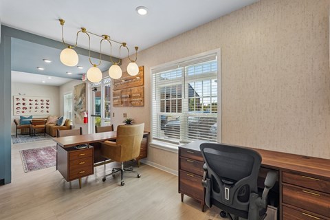 A room with a desk, chairs and a window.