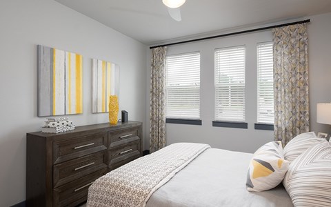 A bedroom with a bed, dresser, and two wall art pieces.