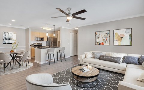 A modern living room with a white sofa, a coffee table, and a dining table set up.