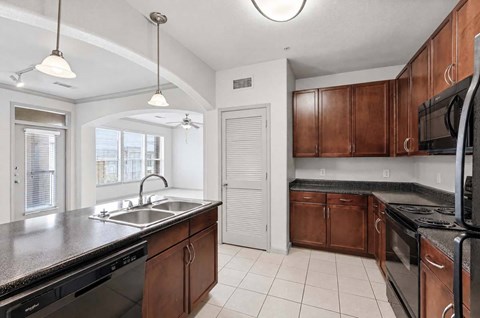 A kitchen with brown cabinets and black appliances.