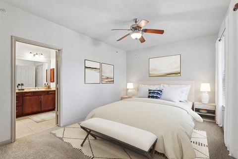 A bedroom with a large bed and a ceiling fan.