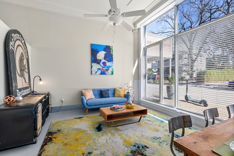 A living room with a blue couch and a painting on the wall.