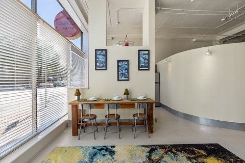 A dining room with a table set for two and a rug on the floor.