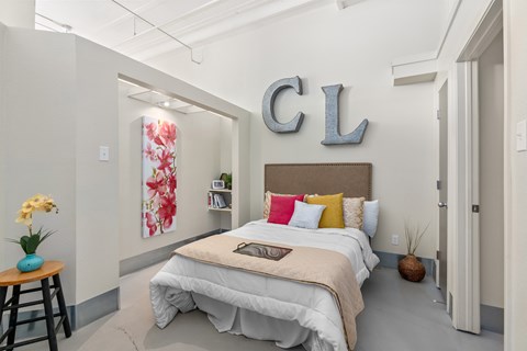 A bedroom with a bed, a table, and a wall with the letters "CL" on it.