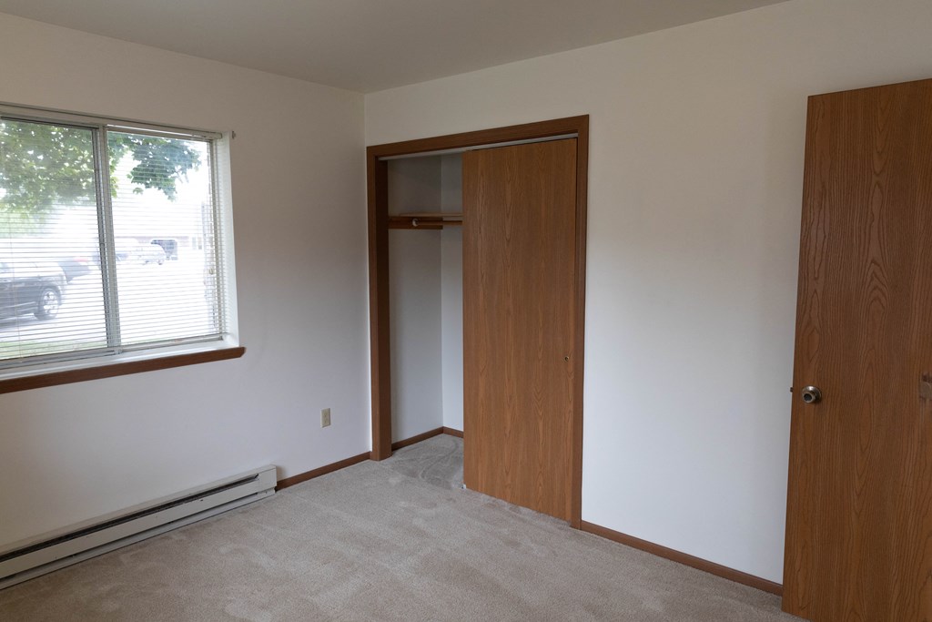 a bedroom with a door to a closet and a window