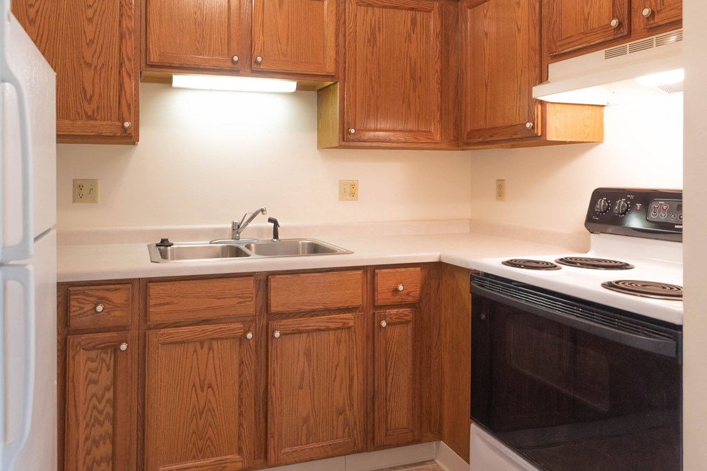 a kitchen with wooden cabinets and a stove and a sink