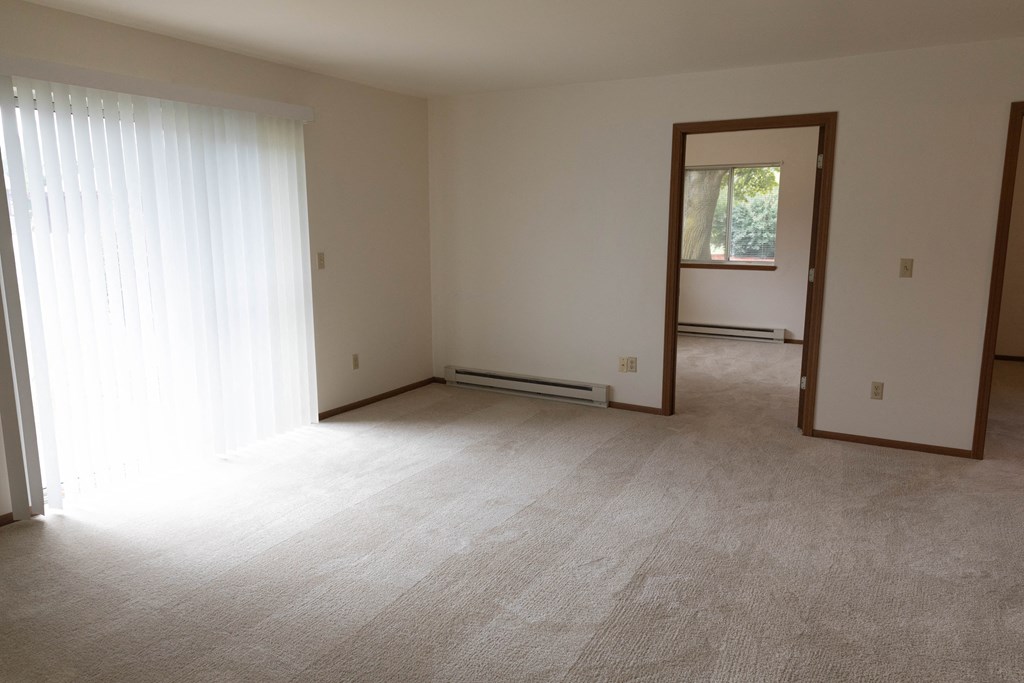 an empty living room with a window and a curtain