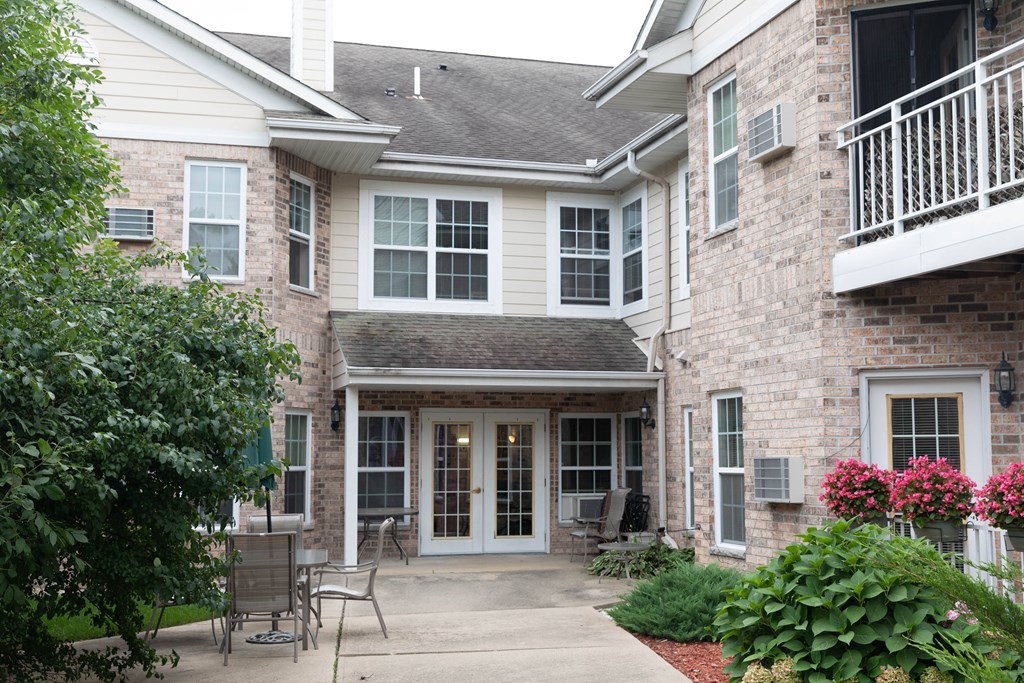 the front entrance of a building with a sidewalk and chairs
