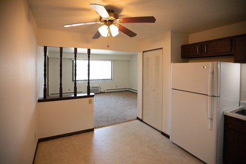 A white refrigerator sits in a kitchen next to a window.
