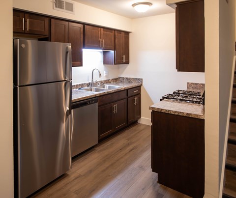 A kitchen with a stainless steel refrigerator and wooden cabinets.