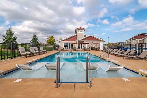 A large outdoor pool with a diving board and lounge chairs.