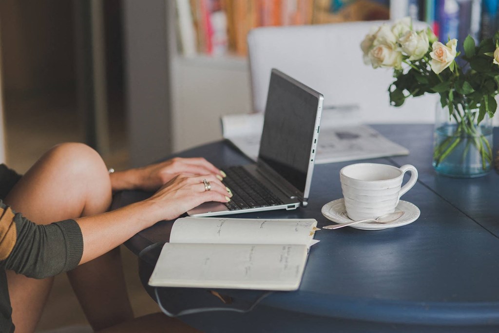 a woman sitting at a table using a laptop computer