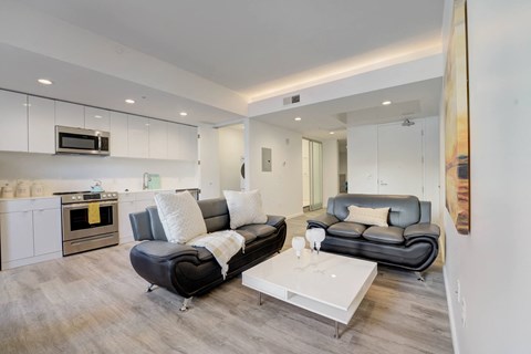 A modern living room with a black leather couch and a white coffee table.