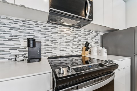 A modern kitchen with a black stove top oven and a black microwave above it.
