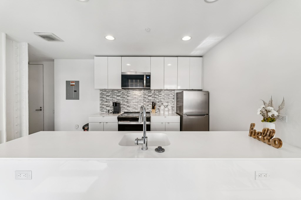 A modern kitchen with a white countertop and stainless steel appliances.