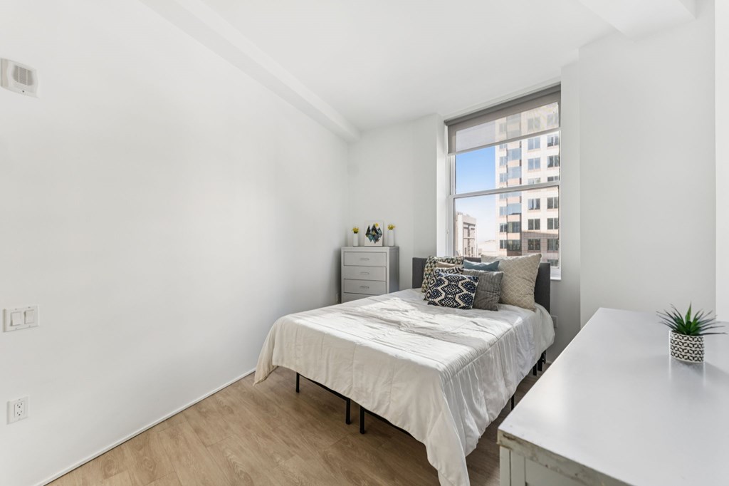 A bedroom with a bed, nightstand, and window.