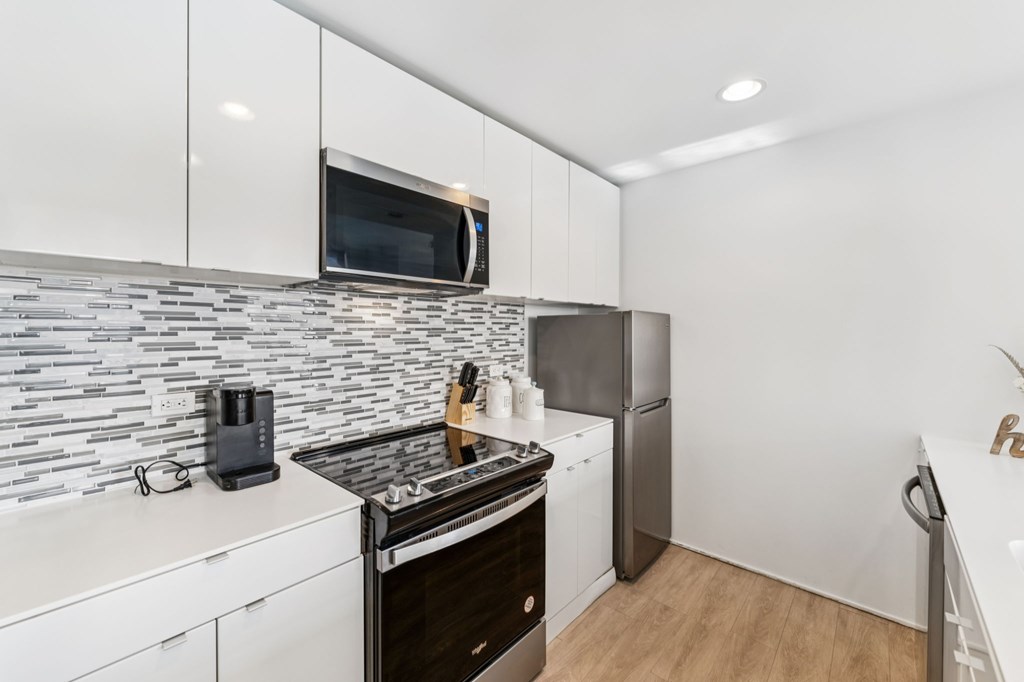 A modern kitchen with a black and white tile backsplash and stainless steel appliances.