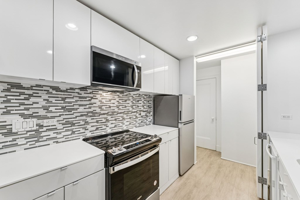 A modern kitchen with a black and white tiled backsplash and stainless steel appliances.