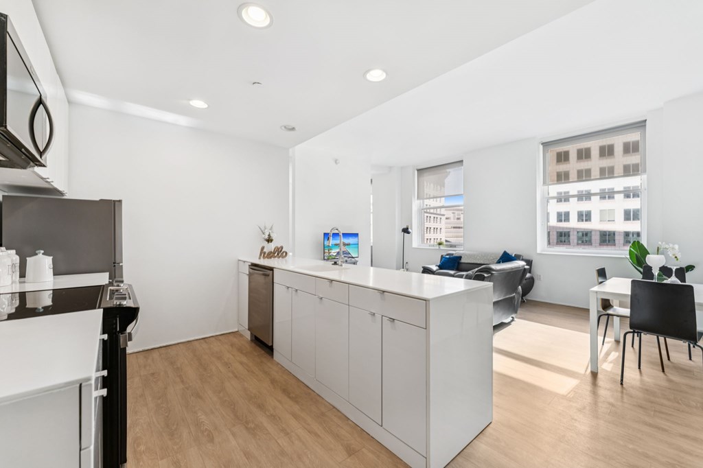 A modern kitchen with white cabinets and a wooden floor.