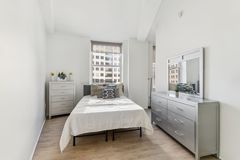 A bedroom with a bed, dresser, and mirror.