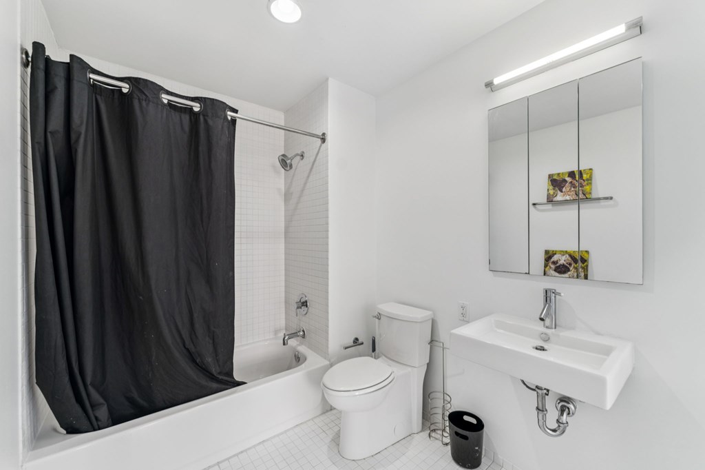 A white bathroom with a black shower curtain.