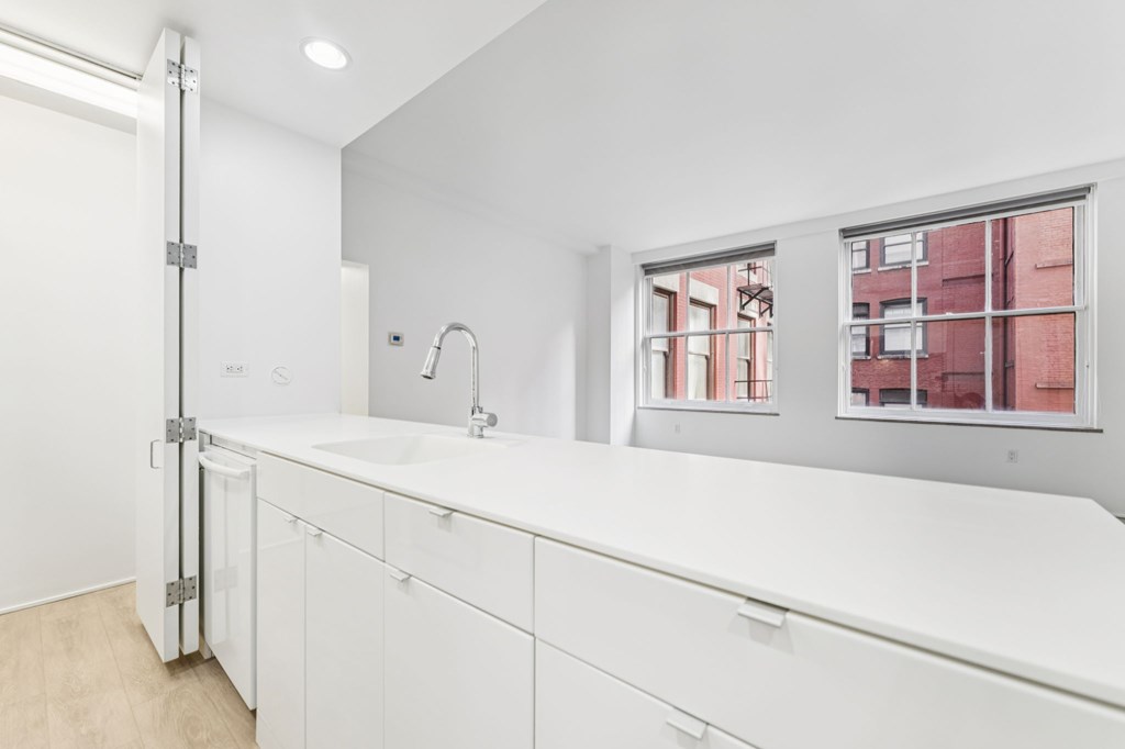 A white bathroom with a sink and a window.